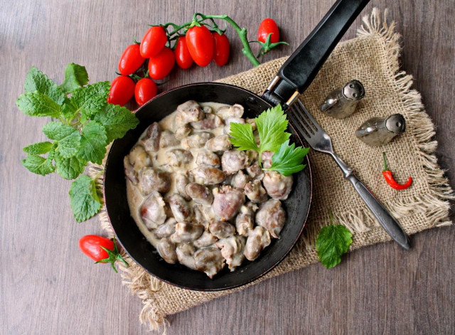 тушковані курячі сердечка в сметані на сковороді з цибулею